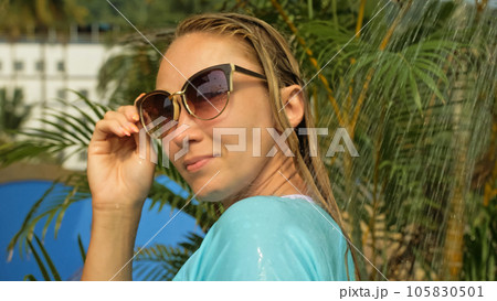 Woman taking a shower in garden near hotel. Girl in blue swimsui Woman taking a shower in garden near hotel. Girl in blue swimsui 105830501