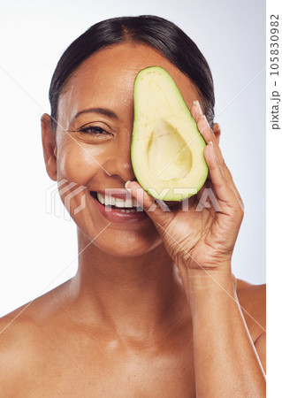Face, skincare and senior woman with avocado in studio isolated on a white background. Happy, natural fruit or portrait of mature model with food for nutrition, healthy diet or omega 3 for anti aging 105830982