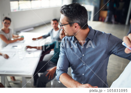 The creative process. a mature man writing on a whiteboard while giving a presentation to colleagues in an office. 105831095