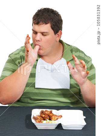Plus sized, eating and man with junk food, unhealthy diet and hungry person isolated on white background. Chicken, weight loss and food addiction problem, male model licking finger at table in studio Plus sized, eating and man with junk food, unhealthy diet and hungry person isolated on white background. Chicken, weight loss and food addiction problem, male model licking finger at table in studio 105831392