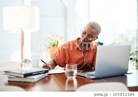 Dream big and do bigger. Shot of a young businesswoman wearing earphones while writing notes in an office. Dream big and do bigger. Shot of a young businesswoman wearing earphones while writing notes in an office. 105832384