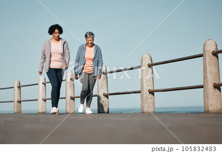 Fitness, walking and senior women by ocean for healthy lifestyle, wellness and cardio on promenade. Sports, friends and female people in conversation on boardwalk for exercise, training and workout 105832483