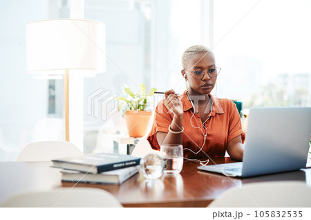 A goal is a dream with a deadline. Shot of a young businesswoman wearing earphones while working on a laptop in an office. 105832535