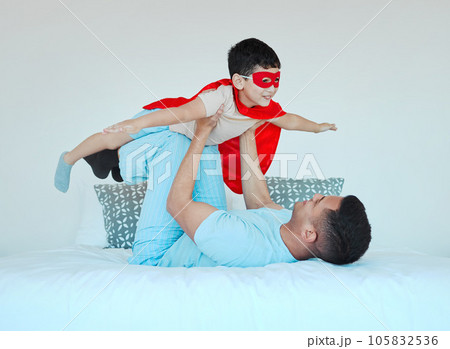 Airplane, bedroom and dad playing with his kid for bonding, fun or happiness at their home. Happy, smile and young father relaxing with his boy child in a superhero costume on the bed at family house Airplane, bedroom and dad playing with his kid for bonding, fun or happiness at their home. Happy, smile and young father relaxing with his boy child in a superhero costume on the bed at family house 105832536