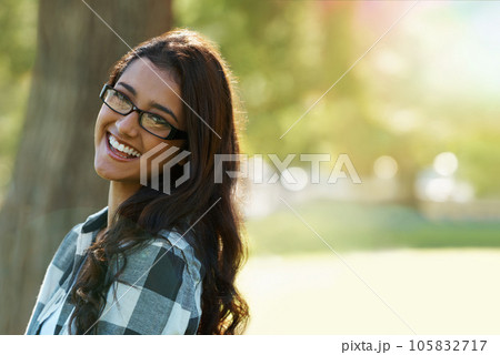 Casual charm. A beautiful ethnic woman standing in a park wearing glasses. 105832717