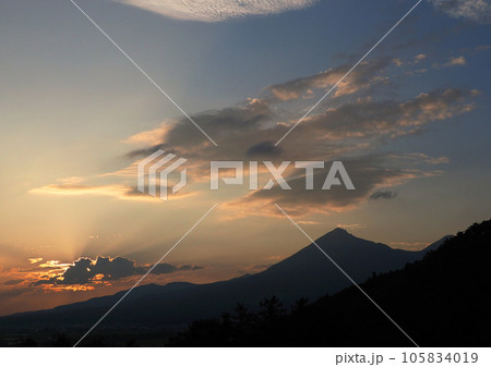 磐梯山の麓に沈む夕日、山のシルエットとオレンジ色に染まる雲、雲からの放射状の光が印象的で綺麗だ。 磐梯山の麓に沈む夕日、山のシルエットとオレンジ色に染まる雲、雲からの放射状の光が印象的で綺麗だ。 105834019