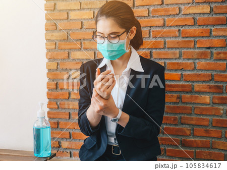 Businesswoman cleaning her hands by using hand sanitizer gel before working in office. 105834617