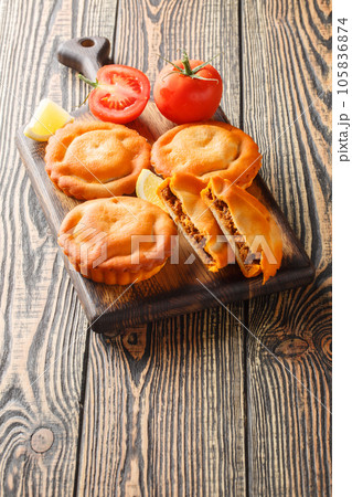 French dish tielles with calamari and tomatoes filling closeup on a wooden board. Vertical French dish tielles with calamari and tomatoes filling closeup on a wooden board. Vertical 105836874