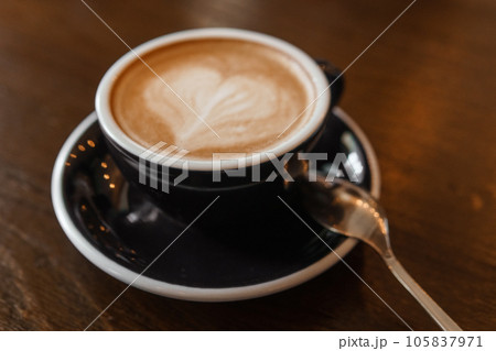 Coffee cup with a heart pattern in a blue cup on a wooden background Coffee cup with a heart pattern in a blue cup on a wooden background 105837971