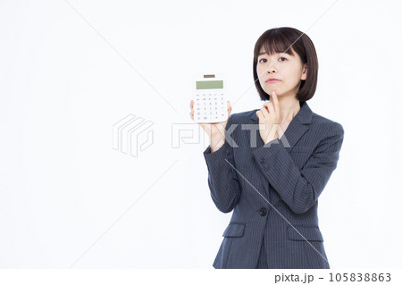 白い背景の前で電卓を持ち悩んでいる30代の働く女性 白い背景の前で電卓を持ち悩んでいる30代の働く女性 105838863