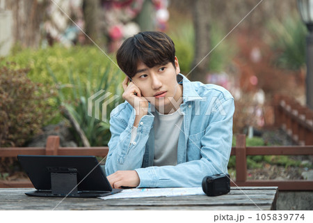 young man with laptop sitting on bench 105839774