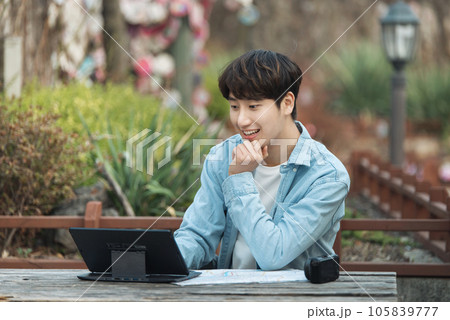 young man with laptop sitting on bench 105839777