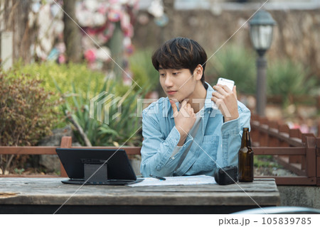 young man with laptop sitting on bench 105839785