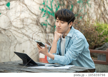 young man with laptop sitting on bench 105839798