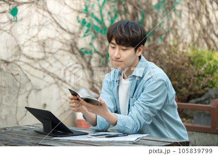 young man with laptop sitting on bench 105839799