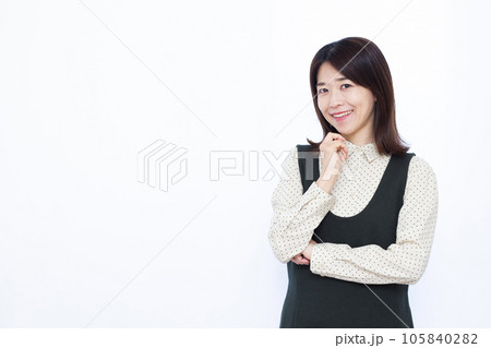 白い背景の前で笑顔で考えている30代の女性 白い背景の前で笑顔で考えている30代の女性 105840282