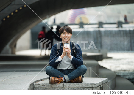 a young man relaxing over a cup of coffee by the city's river a young man relaxing over a cup of coffee by the city's river 105840349