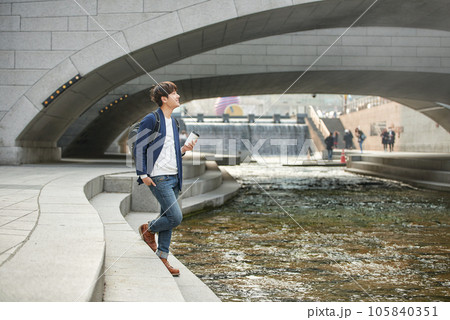 a young man relaxing over a cup of coffee by the city's river a young man relaxing over a cup of coffee by the city's river 105840351