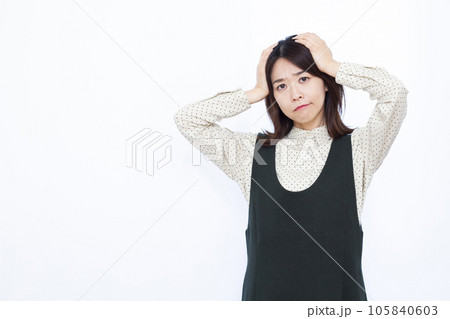 白い背景の前で頭を抱えて悩む30代の女性 白い背景の前で頭を抱えて悩む30代の女性 105840603