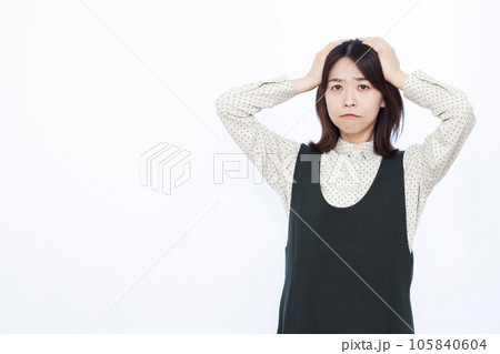 白い背景の前で頭を抱えて悩む30代の女性 白い背景の前で頭を抱えて悩む30代の女性 105840604