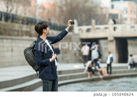a young man with a camera in a park with a river 105840624