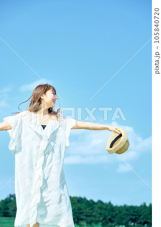 快晴の空の下でリラックスした表情を見せる若い女性 105840720