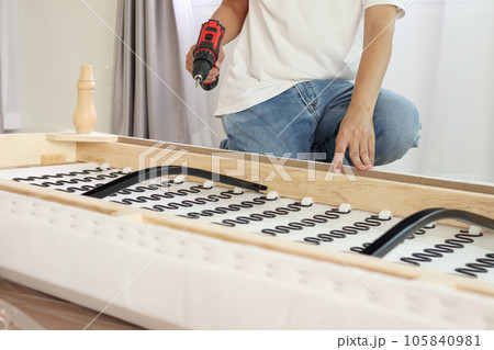 man assembling sofa furniture at home using cordless screwdriver man assembling sofa furniture at home using cordless screwdriver 105840981
