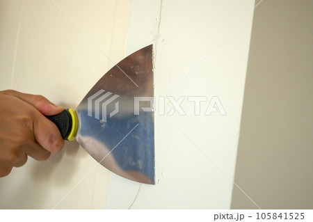 Man repairing crack white wall with spatula 105841525