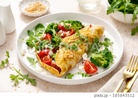 Omelette stuffed with tomato, broccoli feta cheese and fresh green salad. Healthy diet food for breakfast Omelette stuffed with tomato, broccoli feta cheese and fresh green salad. Healthy diet food for breakfast 105843512