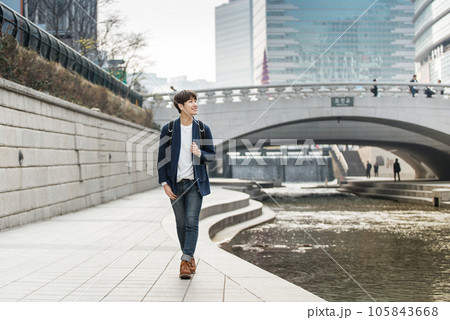 a young man taking a walk in a park with a river in the city 105843668