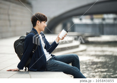 a young man relaxing over a cup of coffee by the city's river 105843855