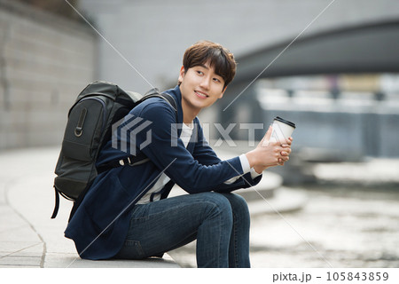 a young man relaxing over a cup of coffee by the city's river 105843859