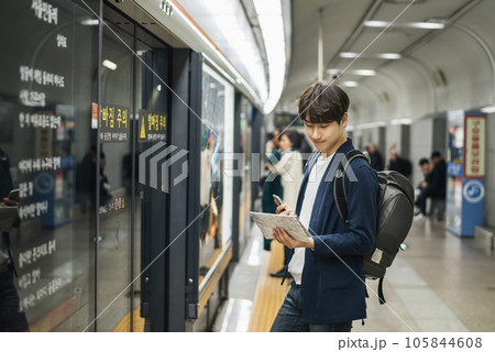 a young man holding a map at a train station a young man holding a map at a train station 105844608