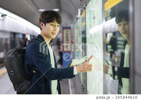 a young man holding a map at a train station 105844610