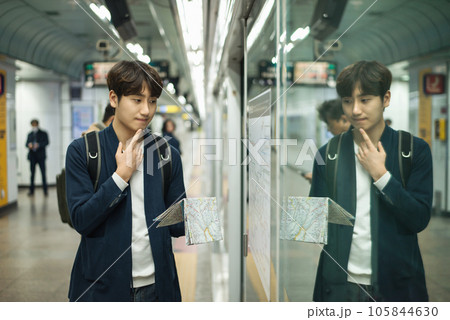 a young man holding a map at a train station 105844630