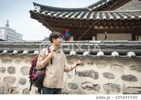 A young man traveling around a traditional village and taking pictures with a smartphone camera 105845500