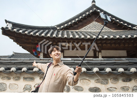 A young man traveling around a traditional village and taking pictures with a smartphone camera 105845503
