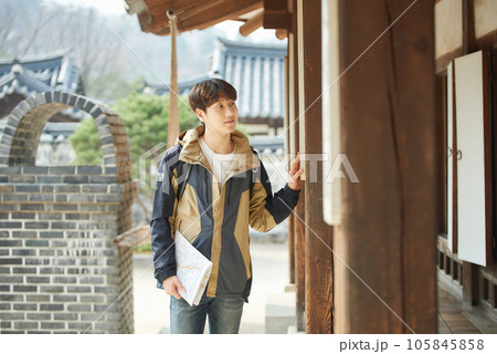 A young male college student who travels with a backpack looking at a map in Korea A young male college student who travels with a backpack looking at a map in Korea 105845858