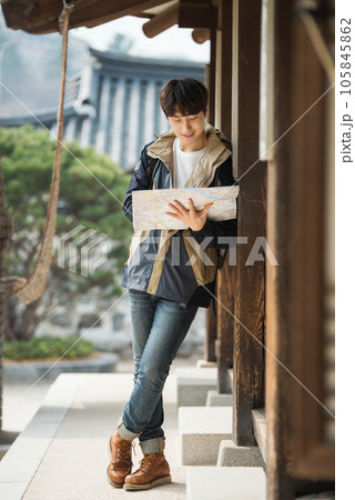 A young male college student who travels with a backpack looking at a map in Korea 105845862