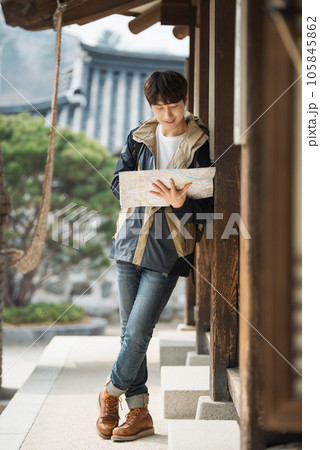 A young male college student who travels with a backpack looking at a map in Korea A young male college student who travels with a backpack looking at a map in Korea 105845862