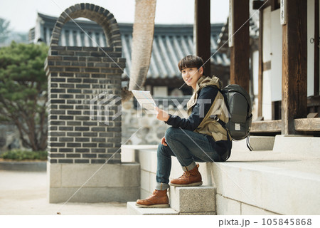 A young male college student who travels with a backpack looking at a map in Korea 105845868