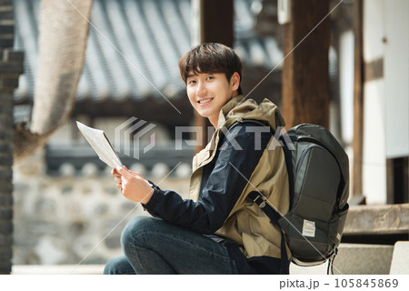 A young male college student who travels with a backpack looking at a map in Korea 105845869