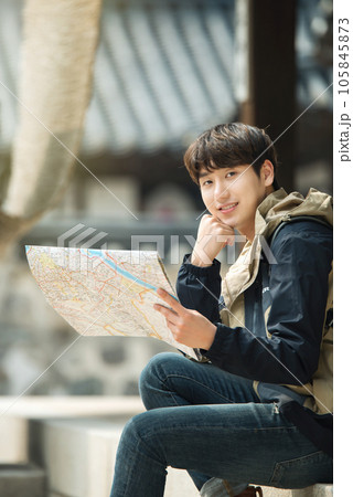 A young male college student who travels with a backpack looking at a map in Korea 105845873