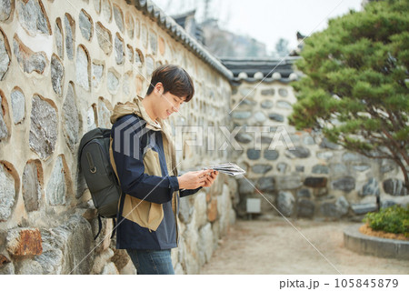 A young male college student who travels with a backpack looking at a map in Korea 105845879