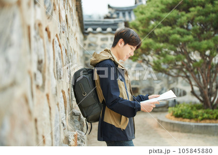 A young male college student who travels with a backpack looking at a map in Korea 105845880