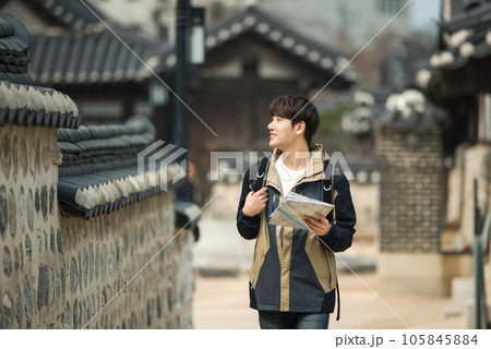 A young male college student who travels with a backpack looking at a map in Korea 105845884