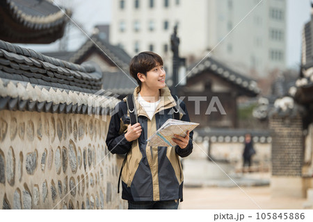 A young male college student who travels with a backpack looking at a map in Korea 105845886