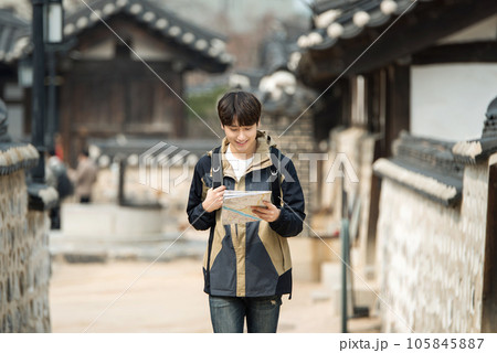 A young male college student who travels with a backpack looking at a map in Korea 105845887