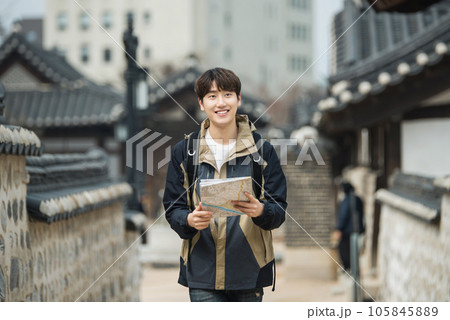 A young male college student who travels with a backpack looking at a map in Korea 105845889