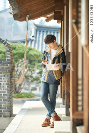 A young male college student looking at a map and searching on his smartphone while traveling to Korea 105845965